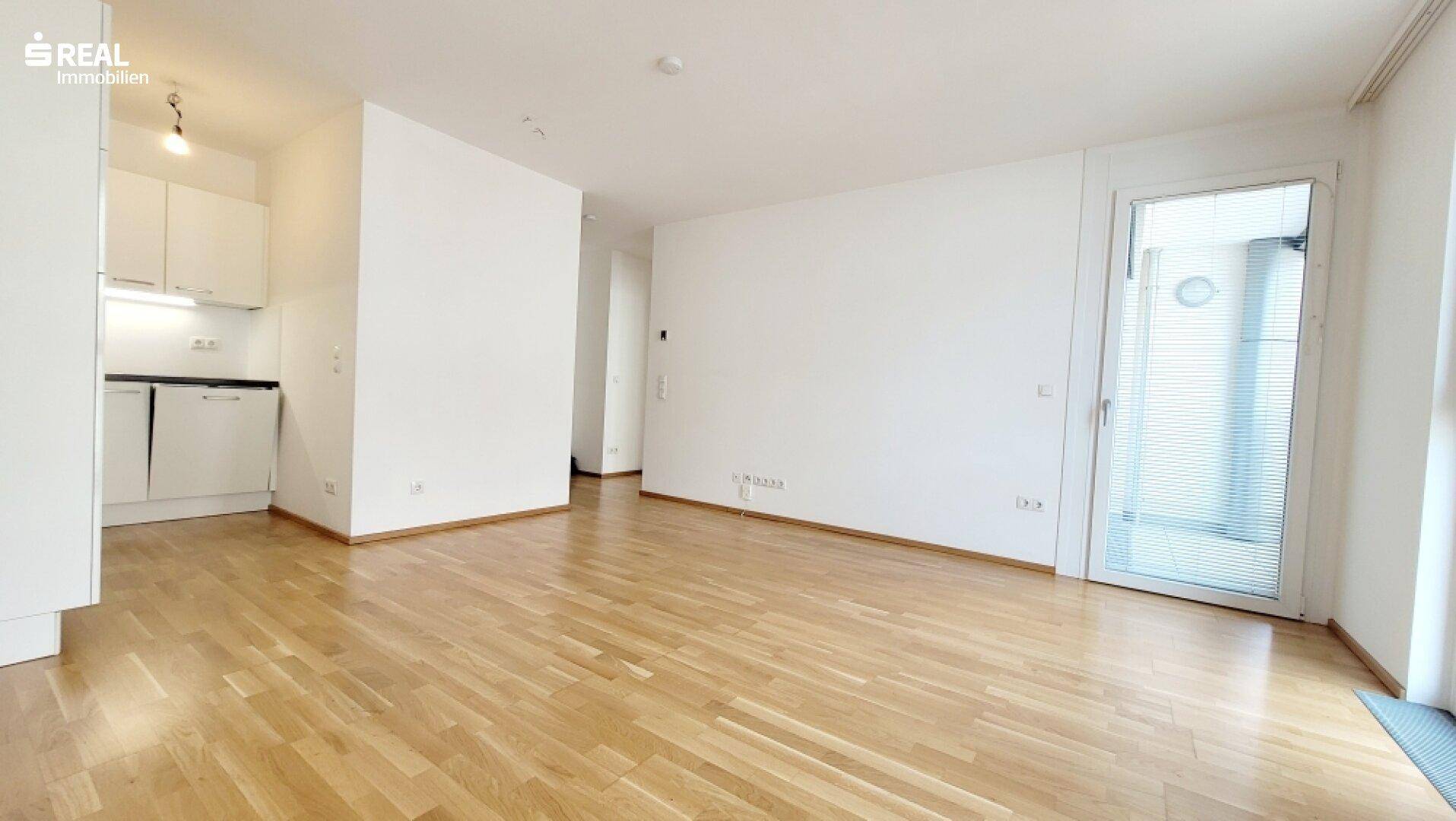 Lichtdurchfluteter Wohnbereich mit Zugang zum Balkon und integrierter Küchenzeile.
