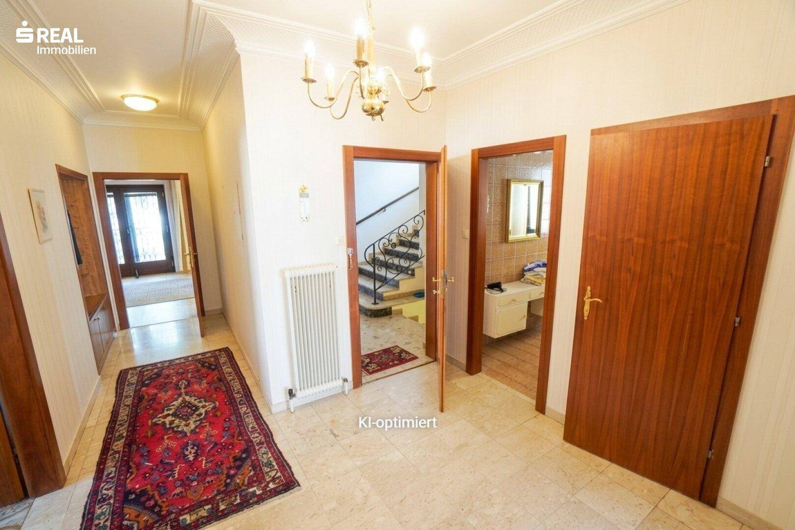 Geräumiger Flur mit Fliesenboden, Holztüren und Zugang zu Treppe und Badezimmer.