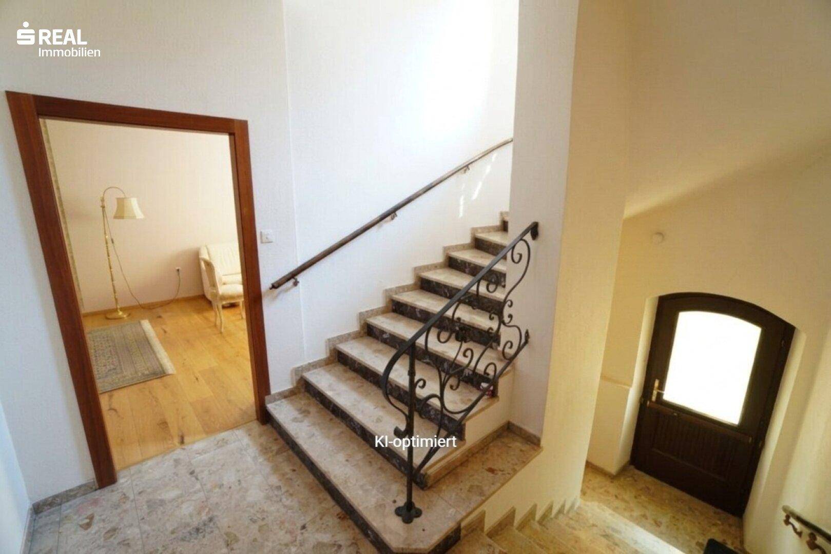 Elegante Steintreppe mit schmiedeeisernem Geländer, die die Etagen verbindet.