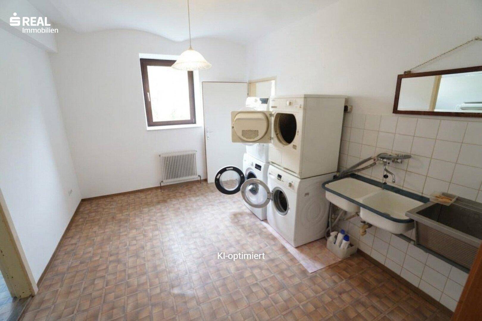 Praktischer Hauswirtschaftsraum mit Waschmaschinen, Spülbecken und Fenster.
