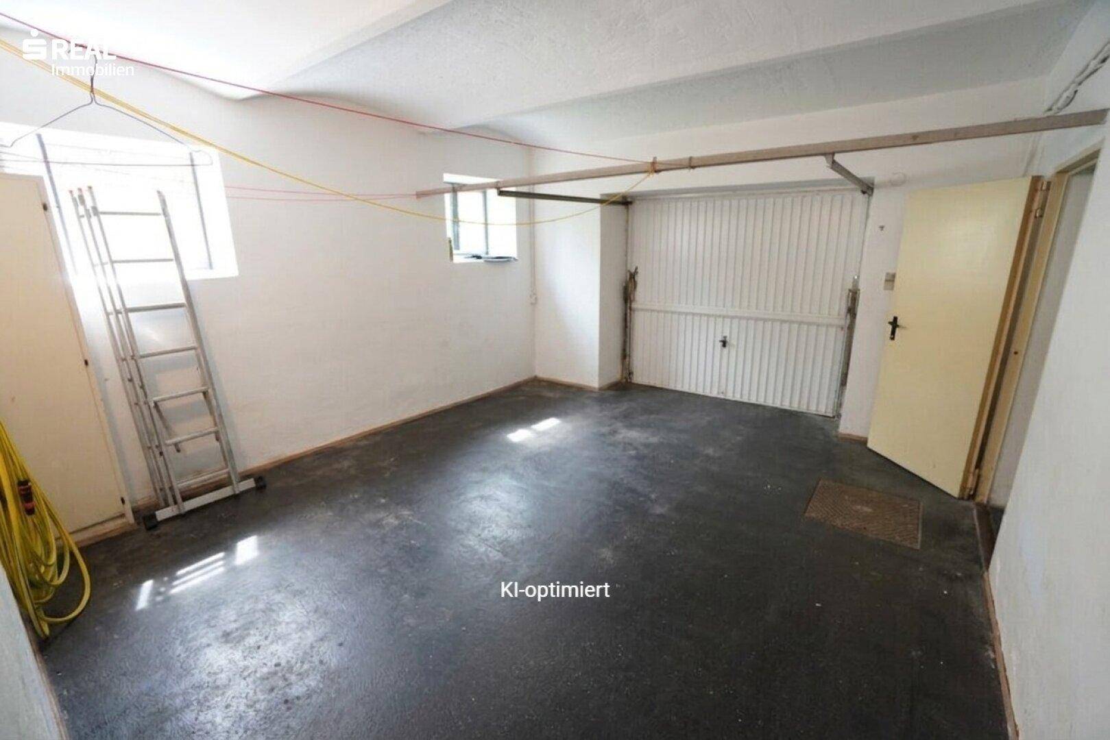 Geräumige Garage mit Betonboden, Garagentor und Fenster für Tageslicht.