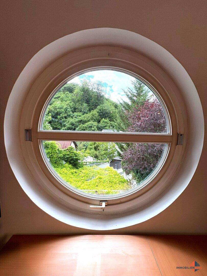 Rundes Fenster bietet einen malerischen Blick ins Grüne und auf die Umgebung.