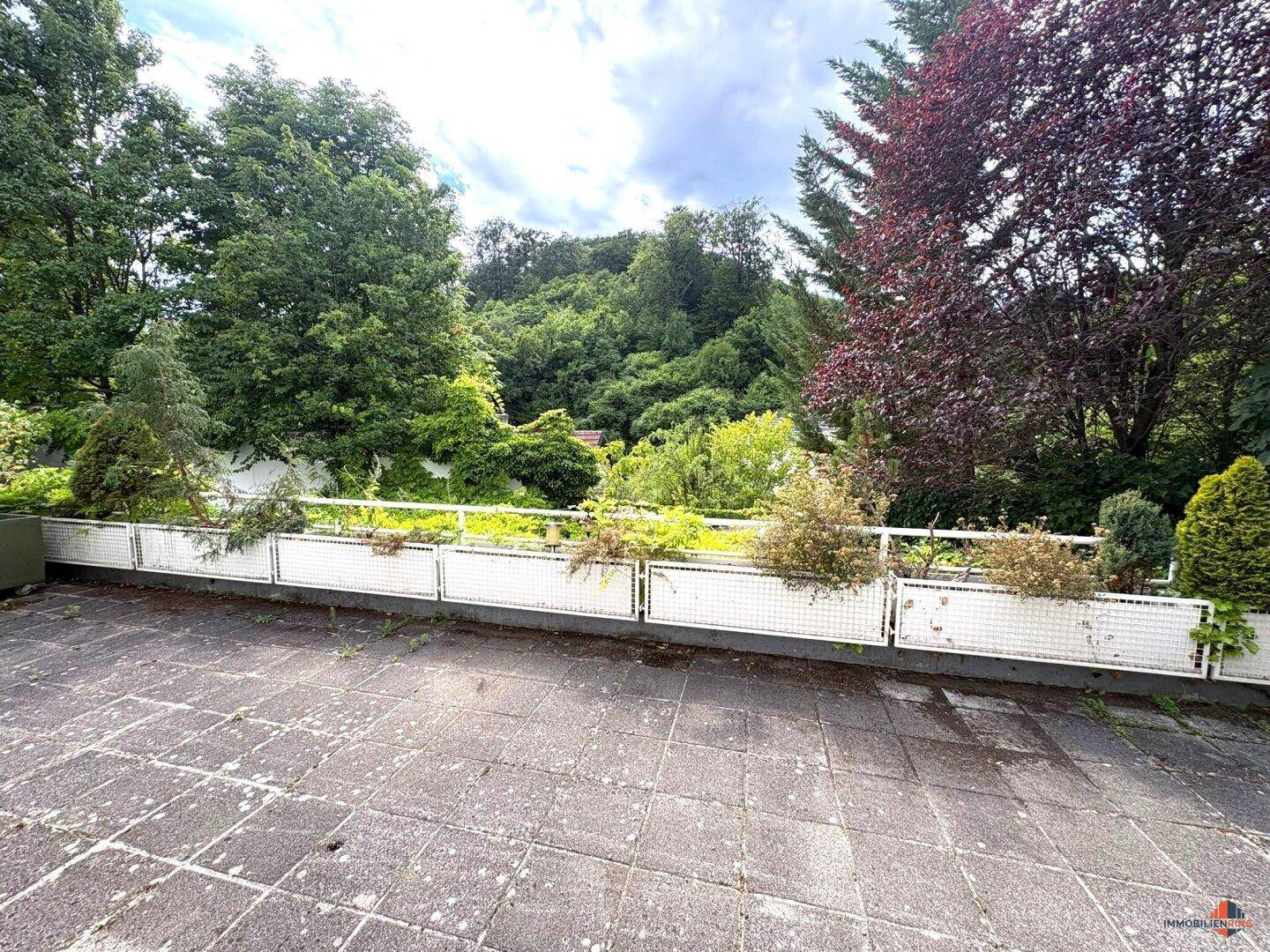 Große, geflieste Terrasse mit Blick ins Grüne, bereit zur individuellen Gestaltung.