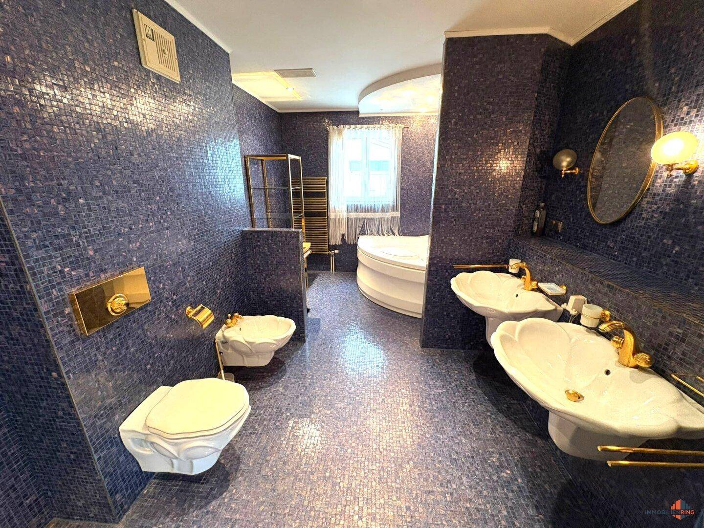 Luxuriöses Badezimmer mit blauen Mosaikfliesen, Doppelwaschbecken und Whirlpool.