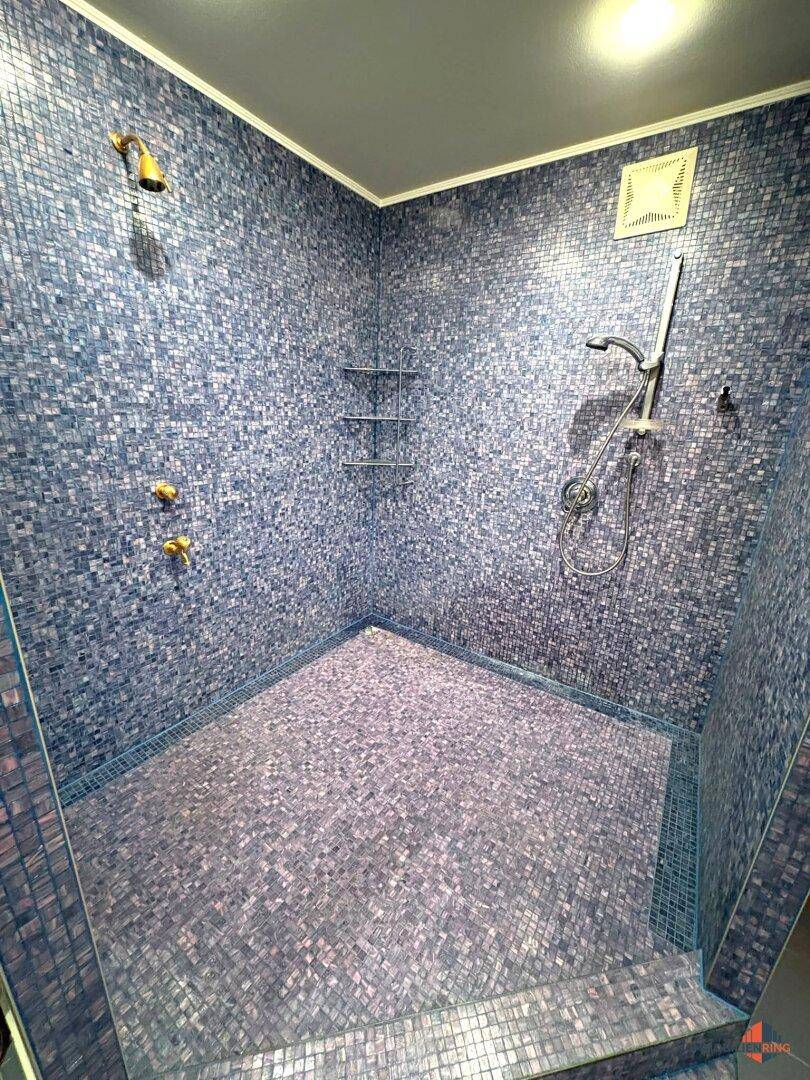 Geräumige Dusche mit blauen Mosaikfliesen und modernen Armaturen.