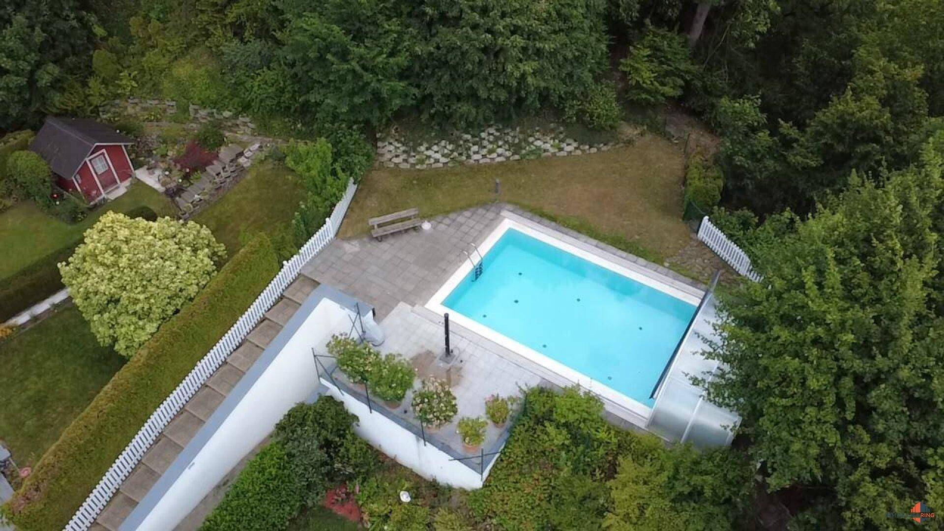 Großer Außenbereich mit privatem Pool, umgeben von viel Grün und Bäumen.