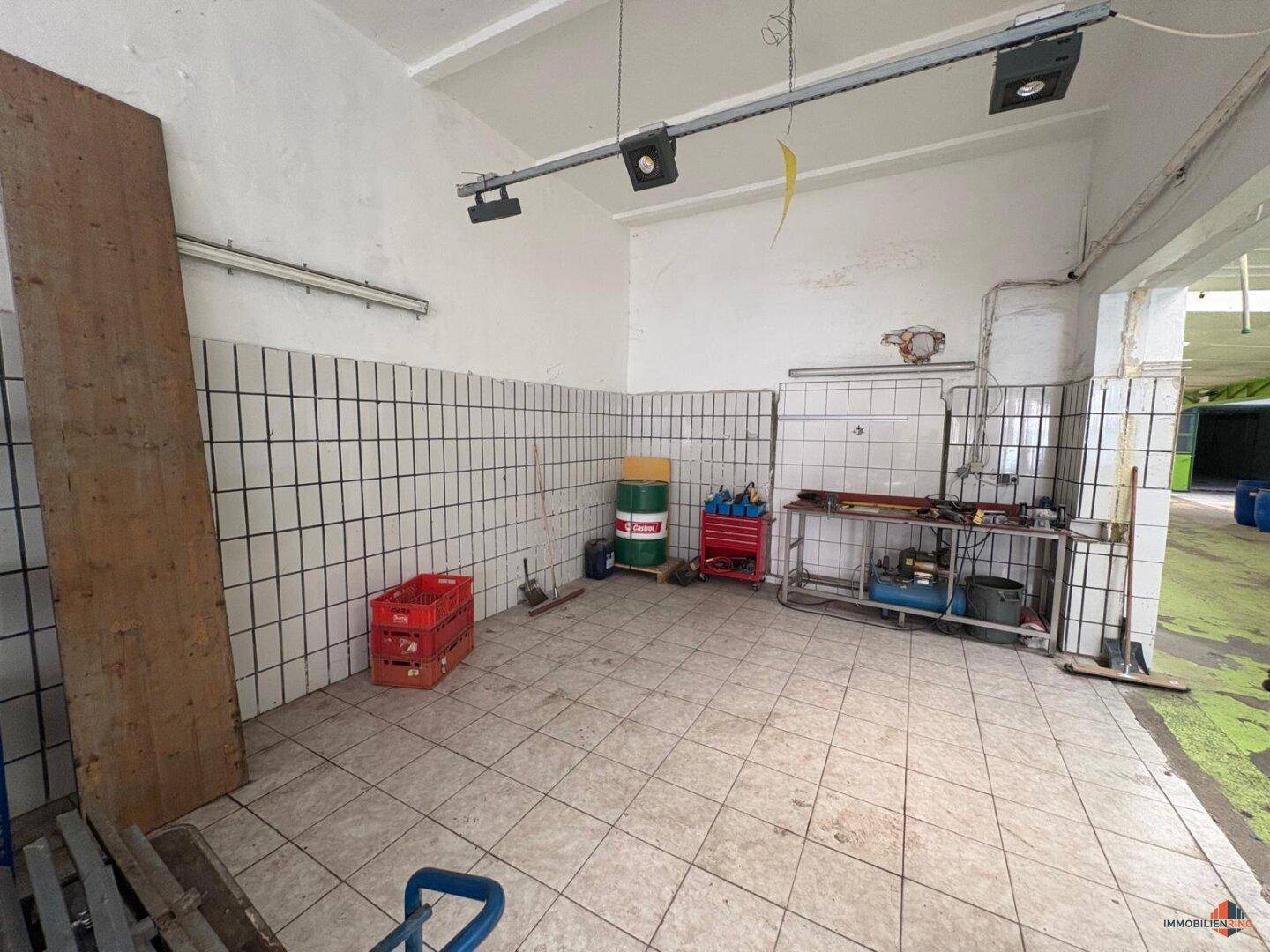 Großer Lagerraum mit weißen Wandfliesen und einer Werkbank, ideal für handwerkliche Arbeiten.