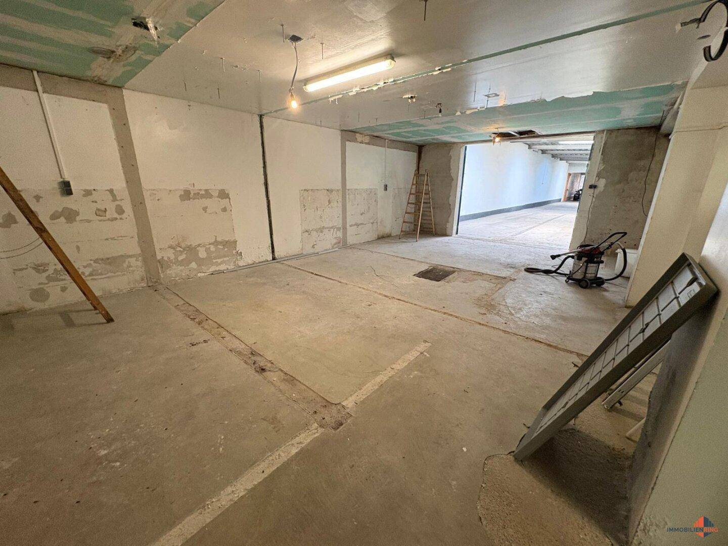 Leerer Raum im Rohbauzustand mit Betonboden und sichtbaren Installationsvorbereitungen.