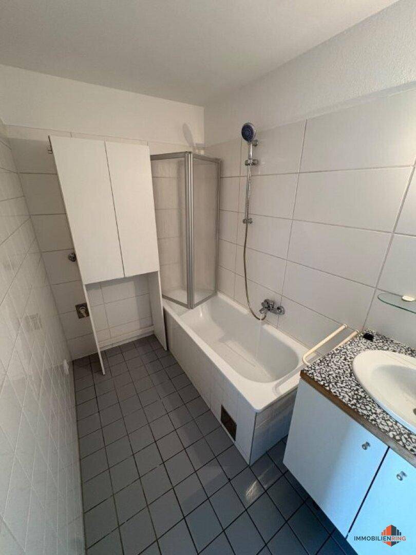 Badezimmer mit Badewanne, Duschabtrennung, Waschbecken und hellen Fliesen, praktisch und gepflegt.