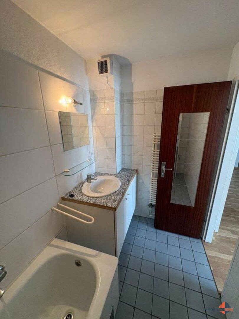 Helles Badezimmer mit Waschbecken, Spiegel und beheiztem Handtuchhalter, modern und funktional.