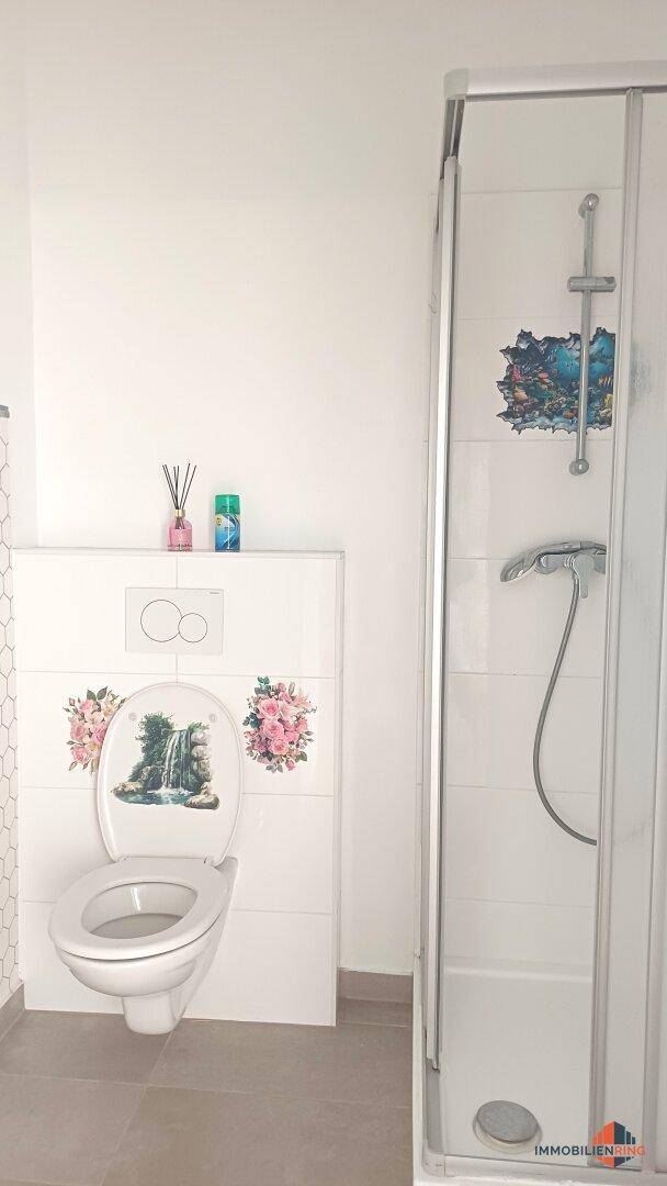 Modernes Badezimmer mit Duschkabine und wandhängendem WC.