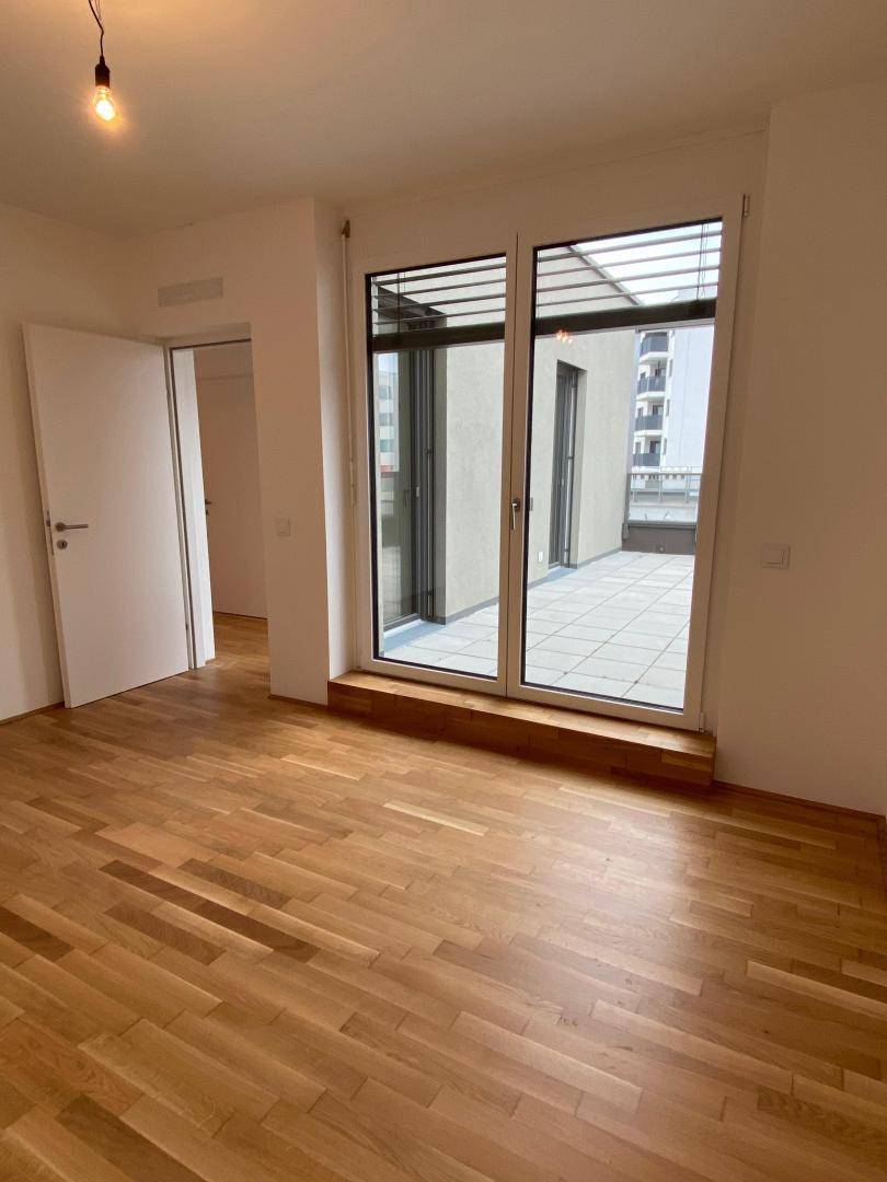 Schlafzimmer mit Holzboden und Zugang zu einer privaten Terrasse, ideal für Entspannung.