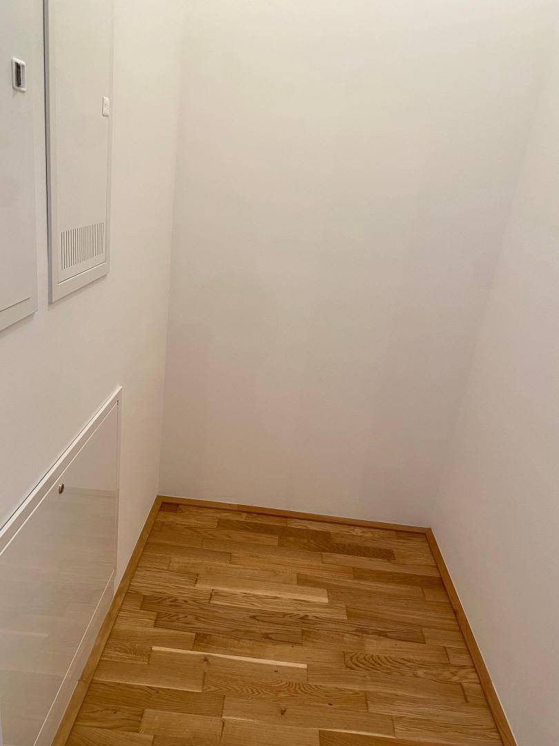 Praktischer Abstellraum mit Holzboden und weißen Wänden, ideal für zusätzlichen Stauraum.