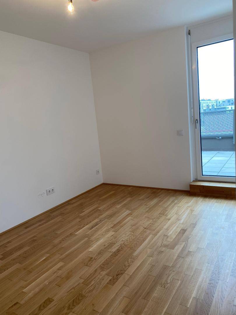 Geräumiges Schlafzimmer mit Parkettboden und Fenster, das viel Tageslicht bietet.
