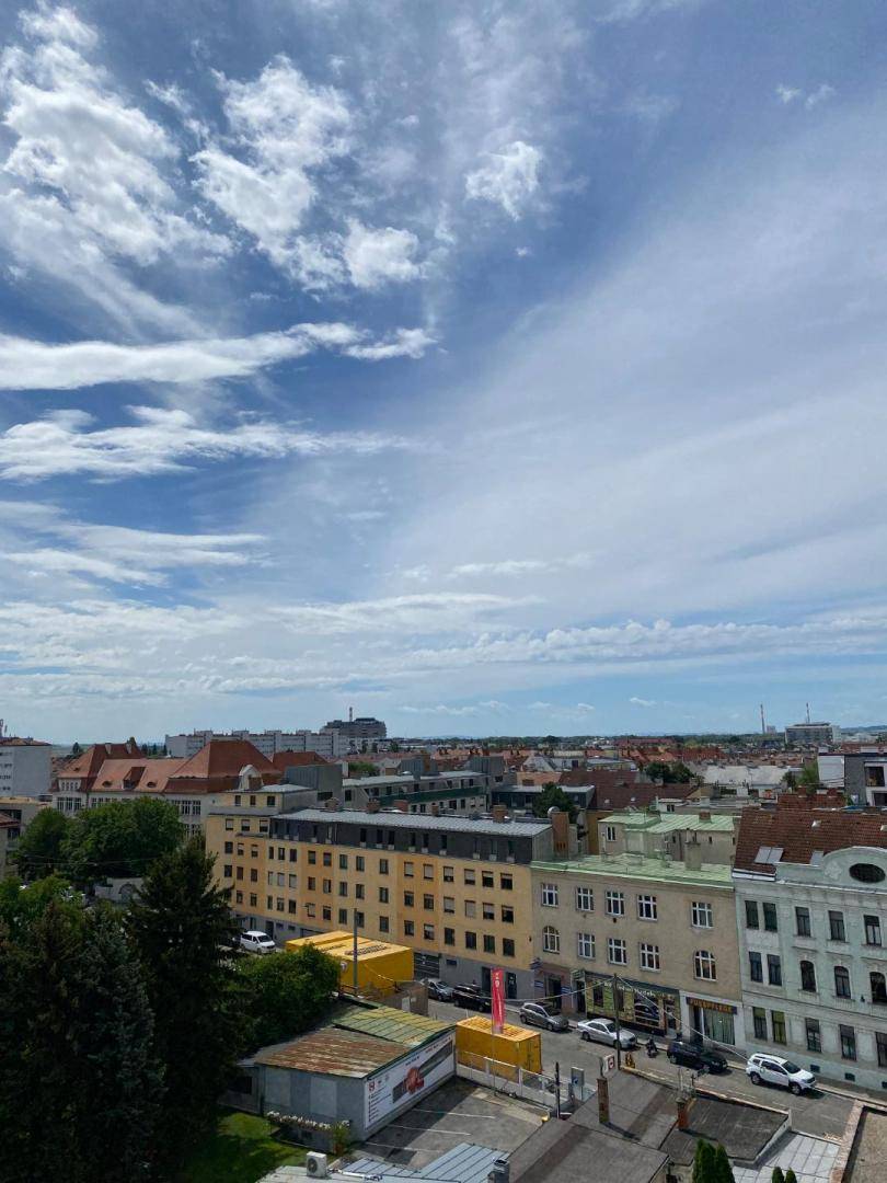 Weitläufiger Blick über die Stadt mit verschiedenen Gebäuden und einem weiten Himmel.