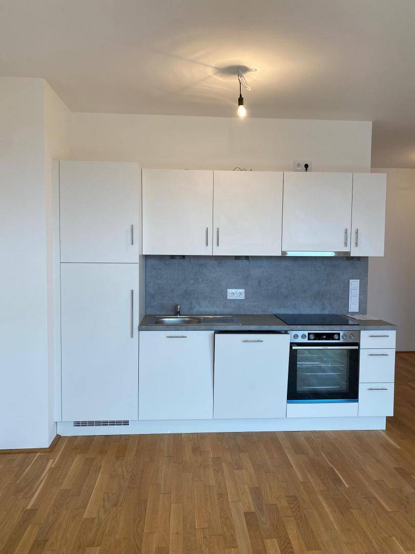 Moderne, weiße Einbauküche mit integrierten Geräten und ausreichend Stauraum.