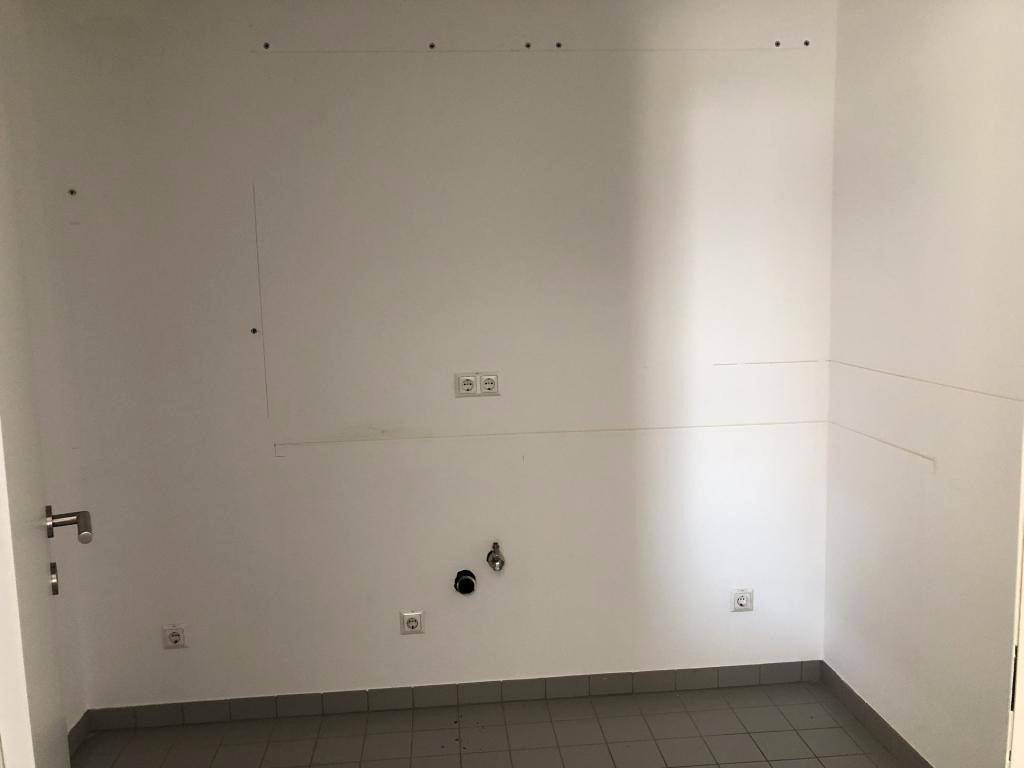 Leerer Hauswirtschaftsraum mit Fliesenboden, Anschlüssen für Wasser und Strom, bereit für Installationen.