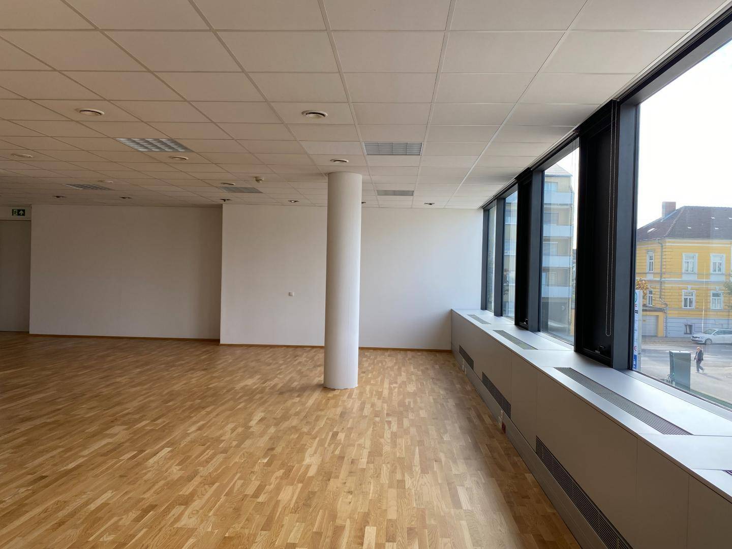 Geräumiger Büroraum mit großen Fenstern, die viel Tageslicht hereinlassen und einen Blick auf die Umgebung bieten.