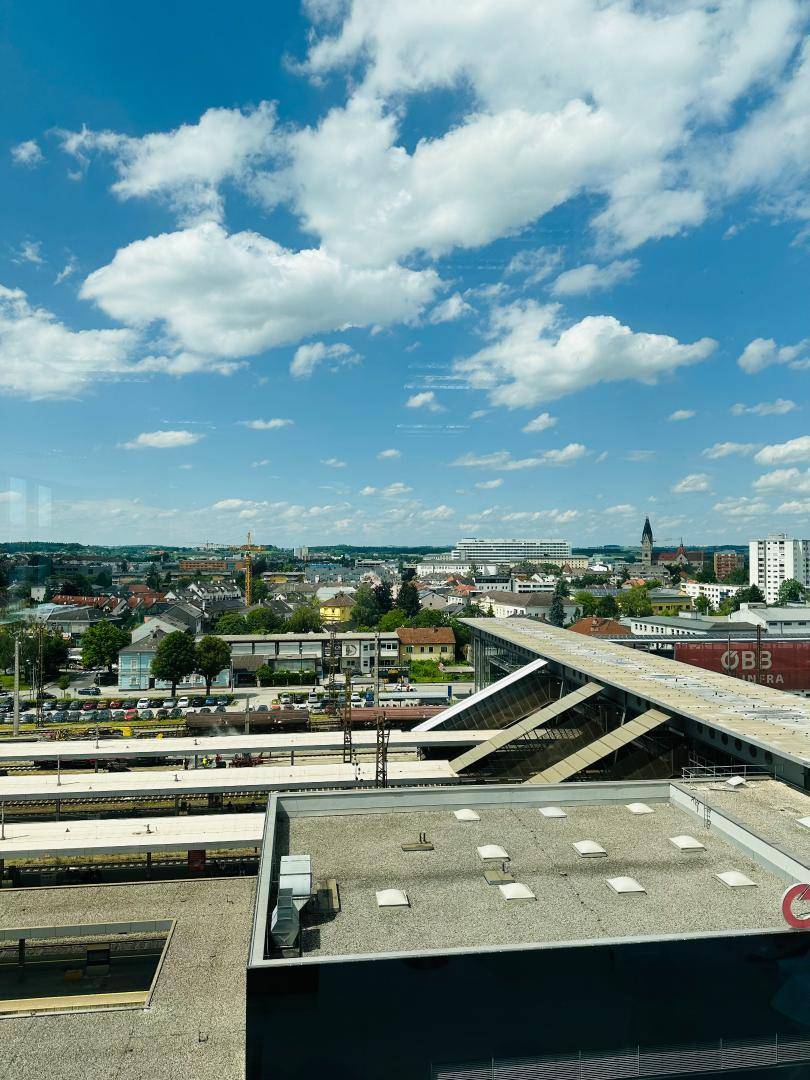 Panoramablick über die Stadt mit Bahnhof, Gebäuden und weitem Horizont.