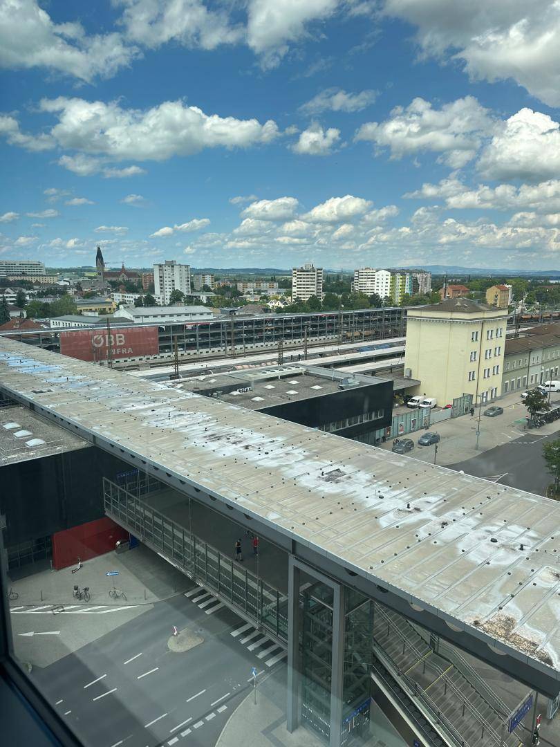 Weitblick über den Bahnhofsbereich mit Gleisen, Gebäuden und Stadtpanorama.