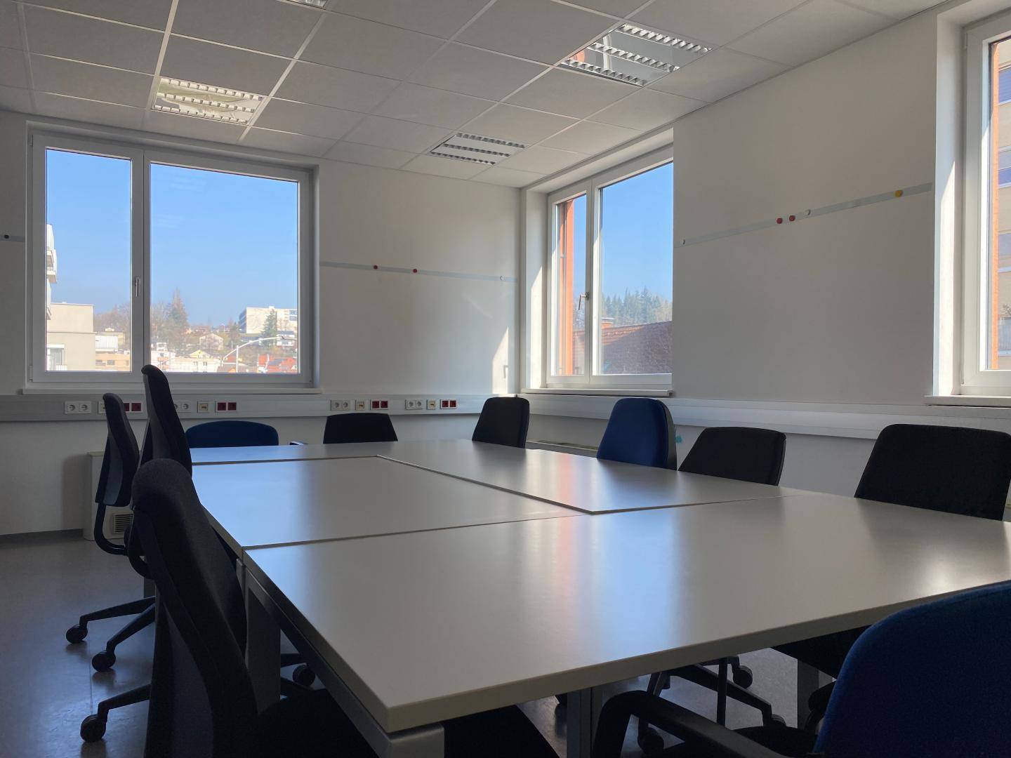 Geräumiger Konferenzraum mit großem Tisch, Bürostühlen und viel Tageslicht durch die Fenster.