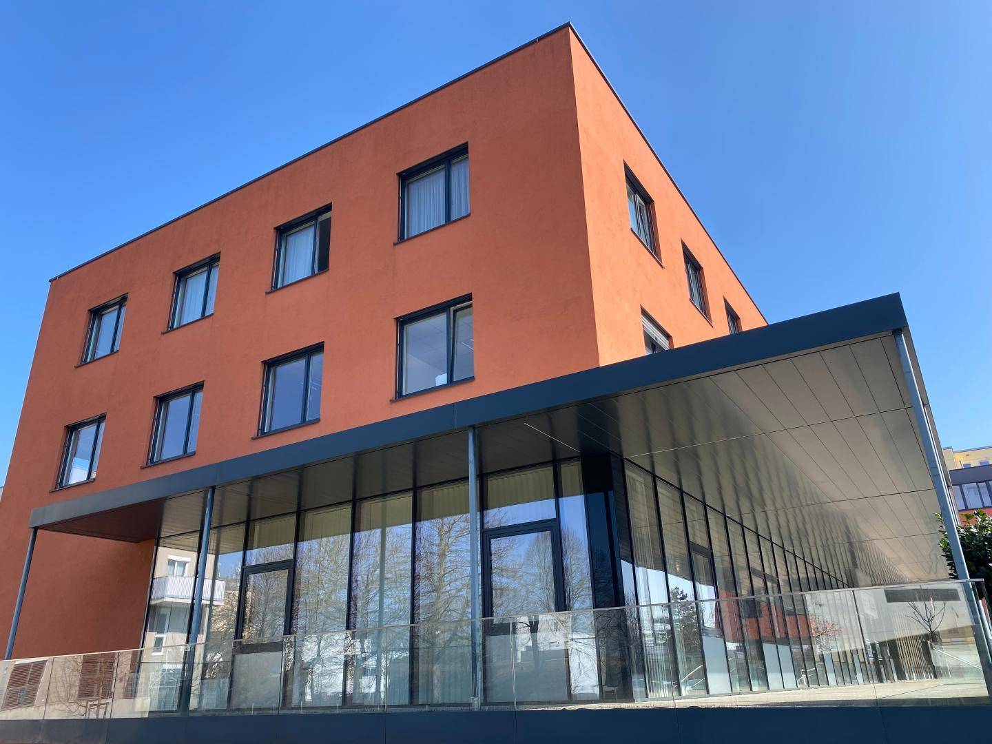 Ansicht eines modernen Geschäftsgebäudes mit orangefarbener Fassade und großer Glasfront.