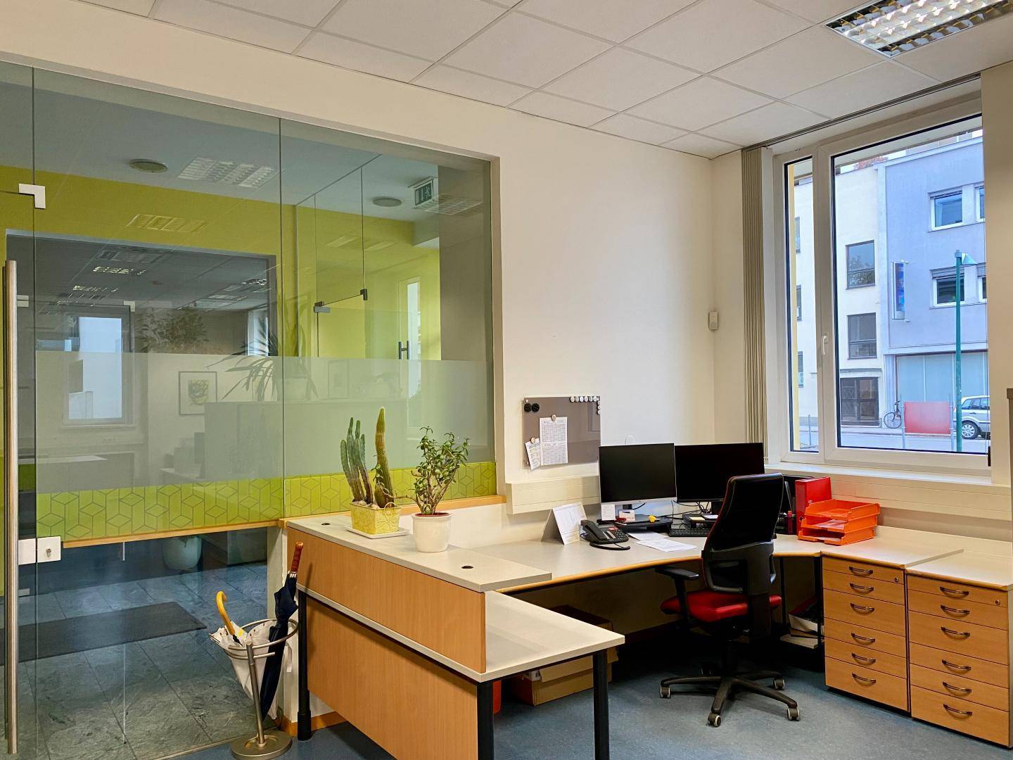 Moderner Bürobereich mit Glastrennwand, Schreibtischen und Blick auf die Straße.