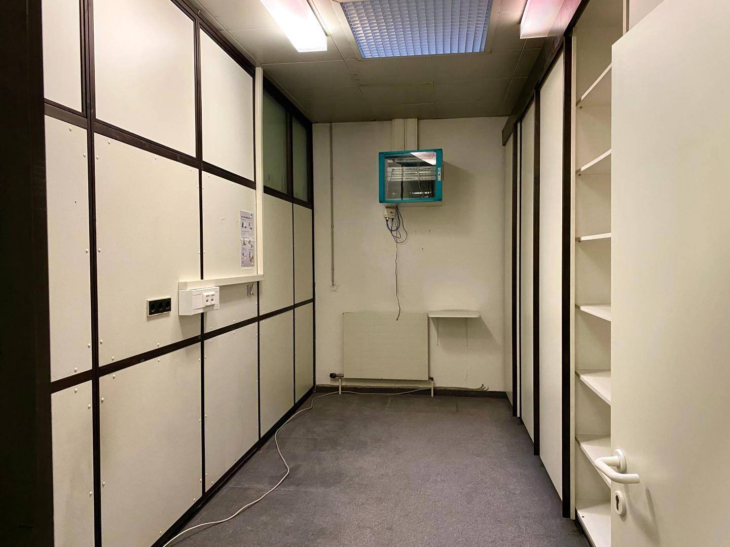 Lagerraum mit modularen Trennwänden, einem Heizkörper und einem Wandgerät.