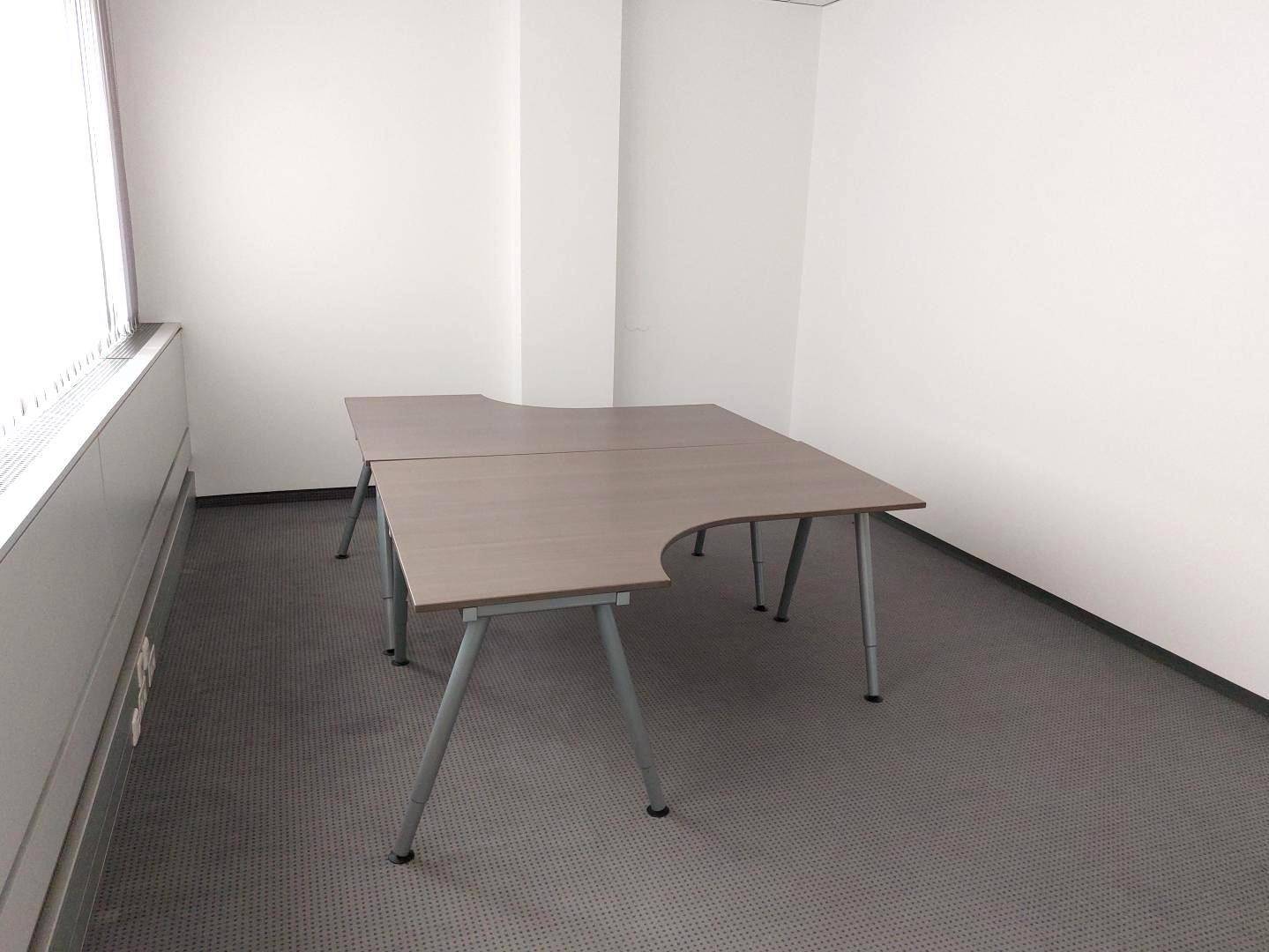 Kleinerer Bürobereich mit zwei Schreibtischen und Teppichboden, ideal für konzentriertes Arbeiten in heller Umgebung.