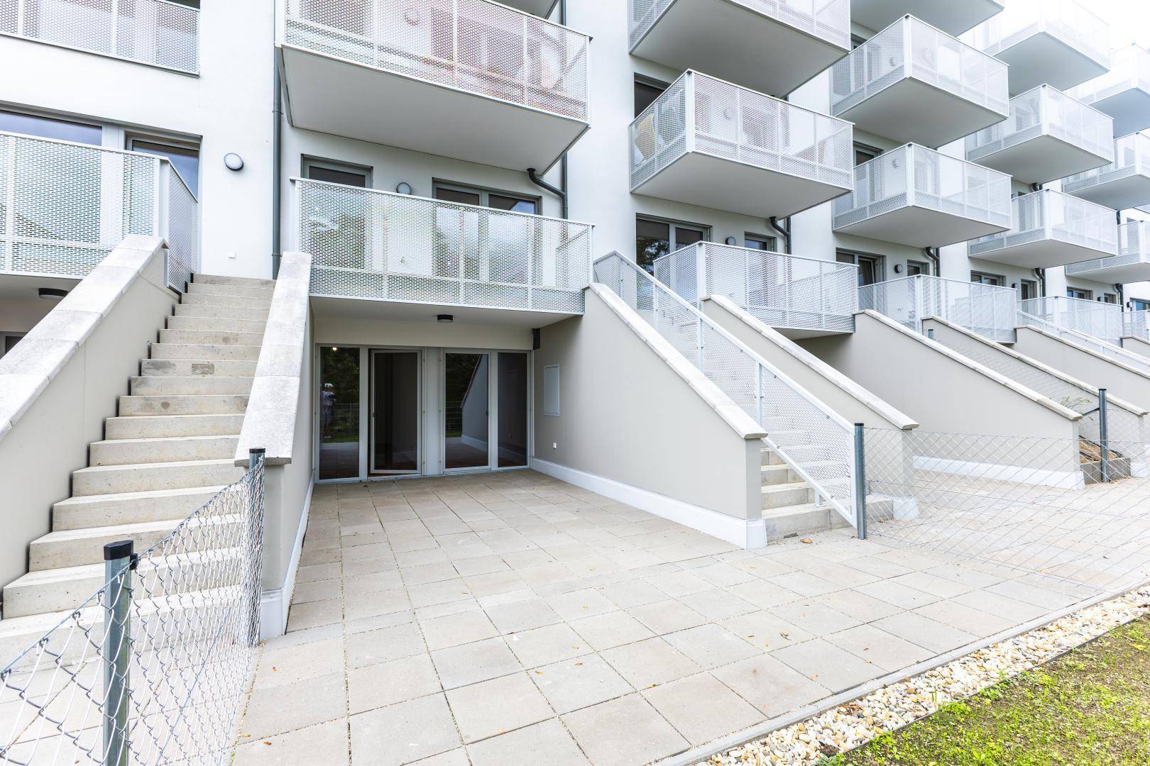Mehrere Terrassen und Treppen an der modernen Fassade eines Wohngebäudes mit Zugang zum Garten.