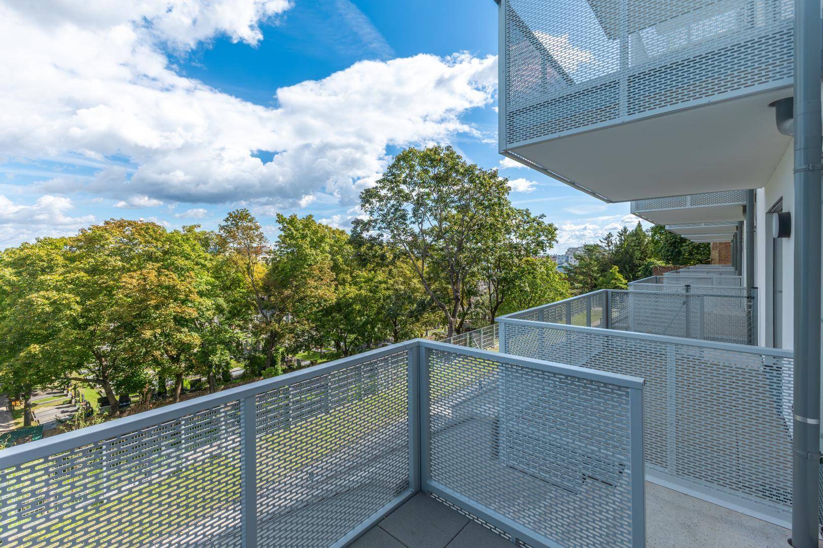 Balkon mit moderner Metallbrüstung und weitem Blick ins Grüne.