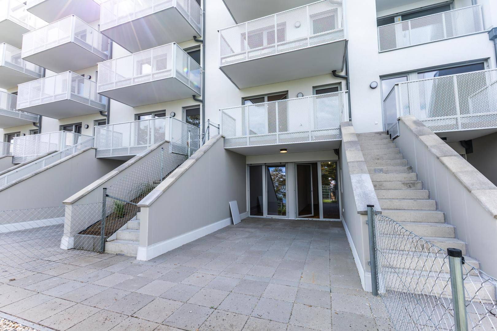 Moderne Gebäudefassade mit mehreren Balkonen und Treppen, die zu den unteren Ebenen führen.