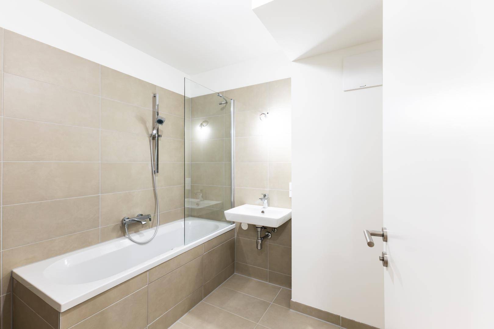 Modernes Badezimmer mit Badewanne, Duschabtrennung aus Glas und beigefarbenen Fliesen.