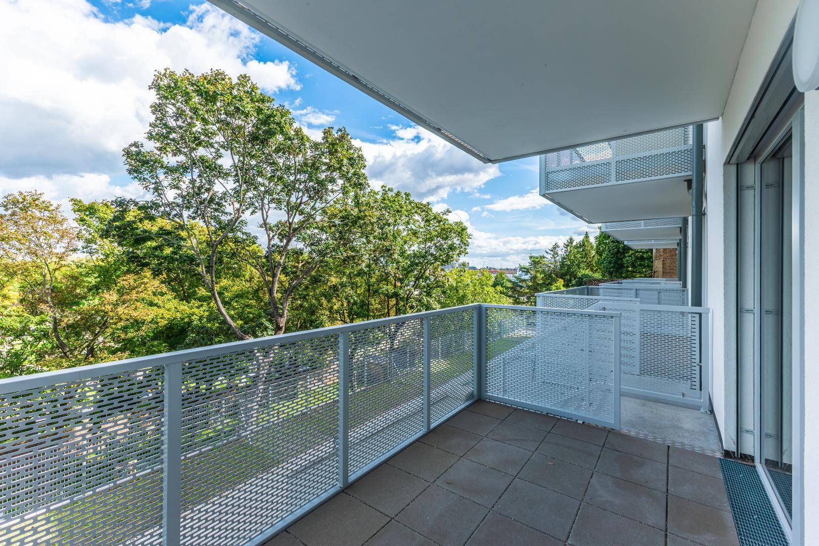 Geräumiger Balkon mit modernem Metallgeländer und weitem Blick ins Grüne.