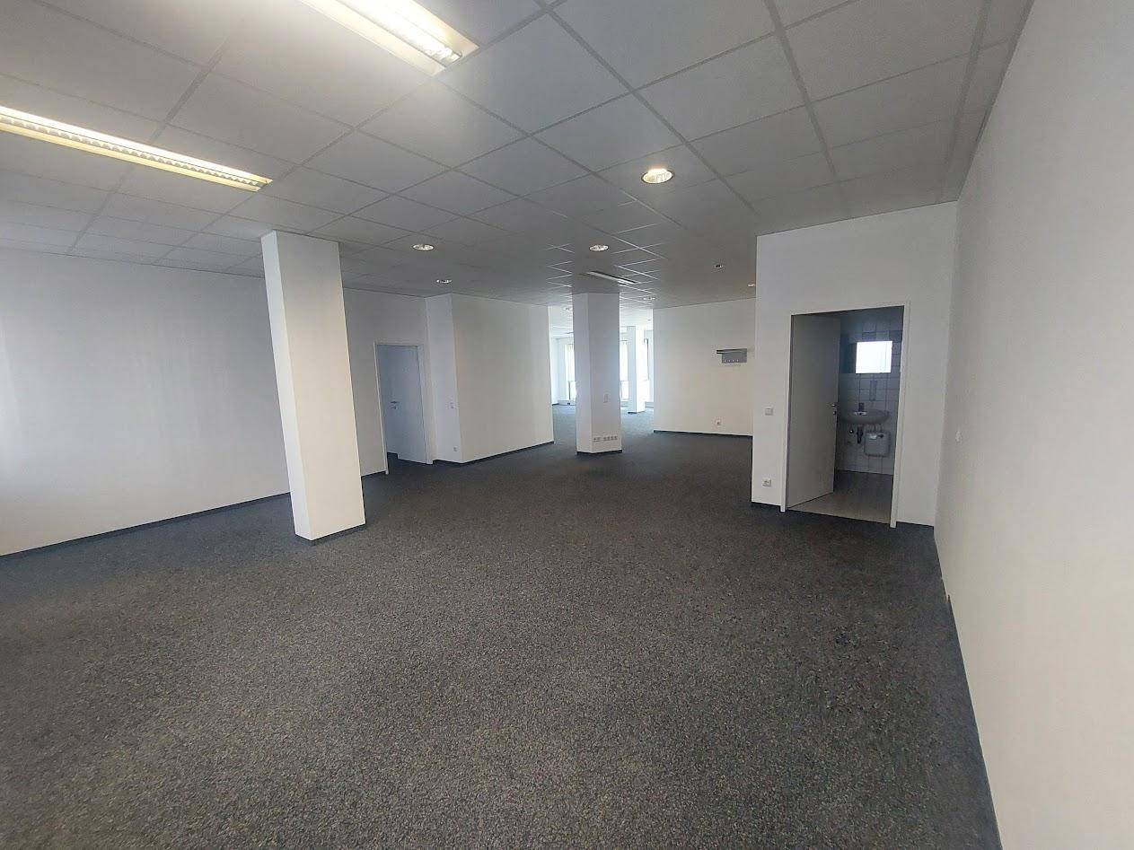 Großes, offenes Büro mit Teppichboden und Zugang zu Sanitärräumen, bietet vielseitige Nutzungsmöglichkeiten.