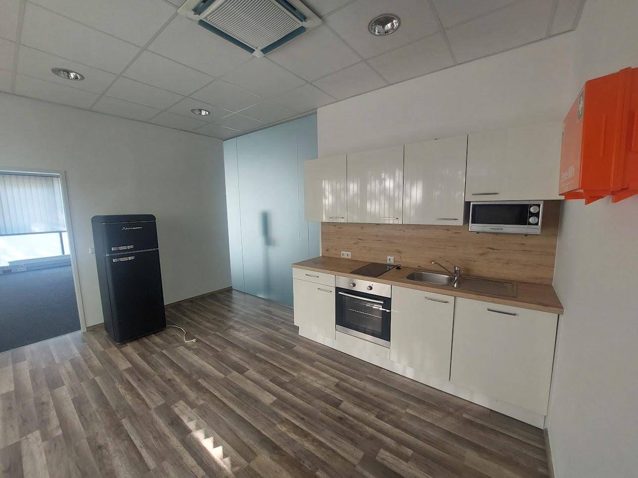 Moderne Küchenzeile mit weißen Schränken, Holzoptik-Arbeitsplatte und integrierten Geräten, ideal für Pausen.