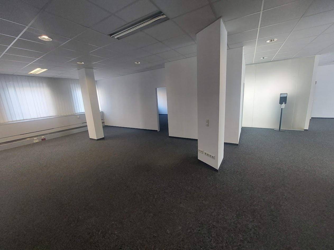 Großes, offenes Büro mit Säulen und Teppichboden, bietet flexible Gestaltungsmöglichkeiten für Arbeitsbereiche.