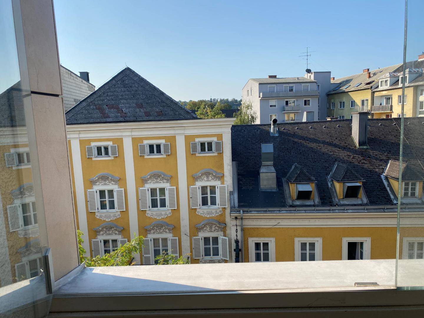 Blick aus dem Fenster auf charmante Altbauten mit gelben Fassaden und traditionellen Dächern.