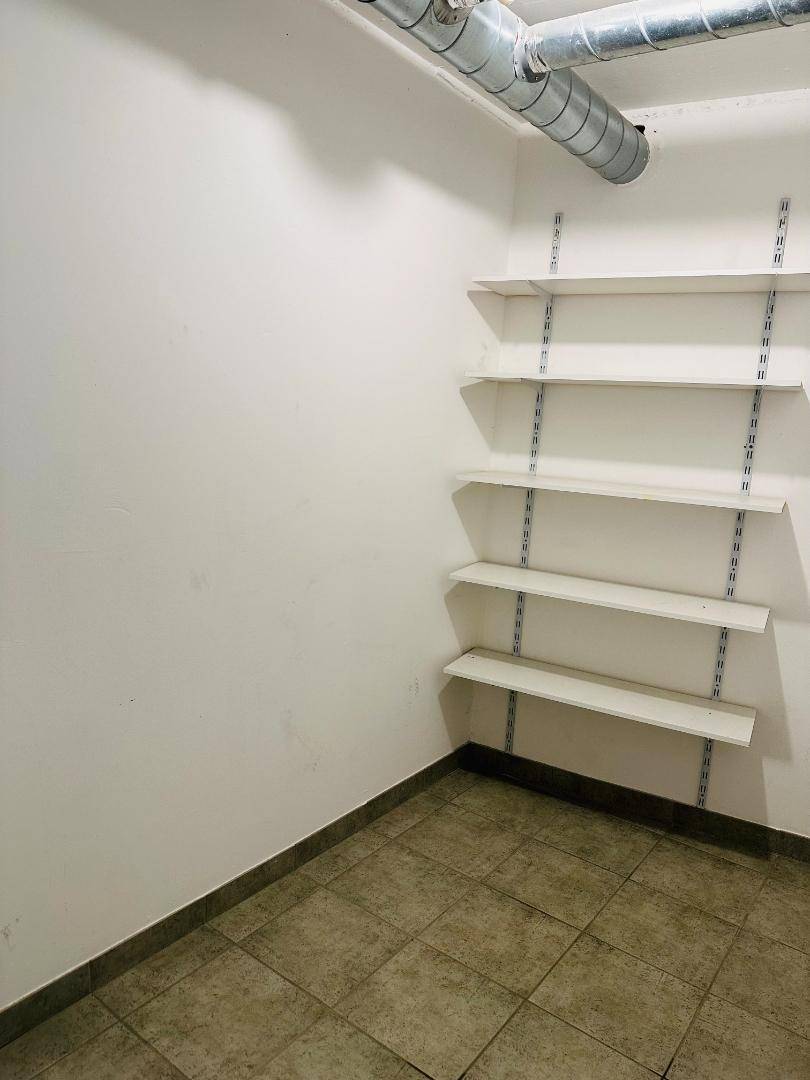Praktischer Abstellraum mit verstellbaren Regalen und sichtbaren Leitungen an der Decke.