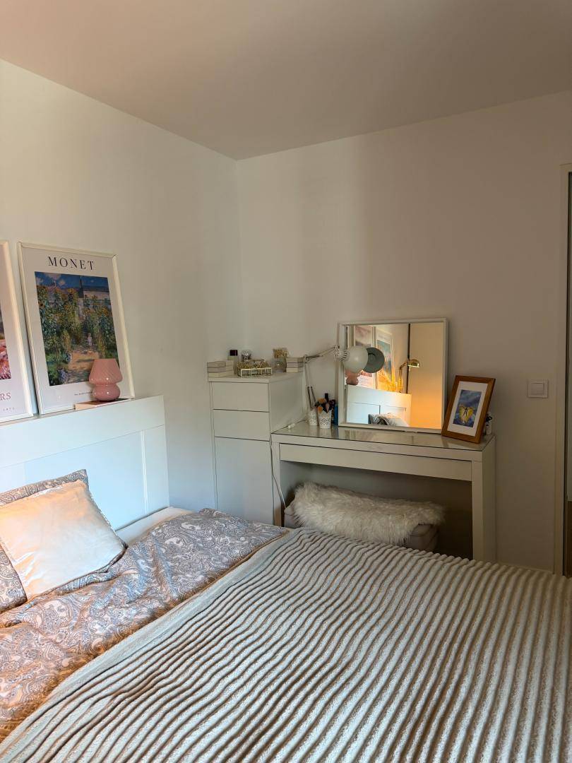 Schlafzimmer mit Bett, Schminktisch und heller Einrichtung.