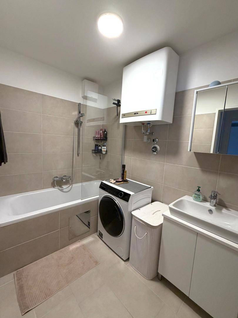 Modernes Badezimmer mit Badewanne, Dusche, Waschbecken und Waschmaschine.