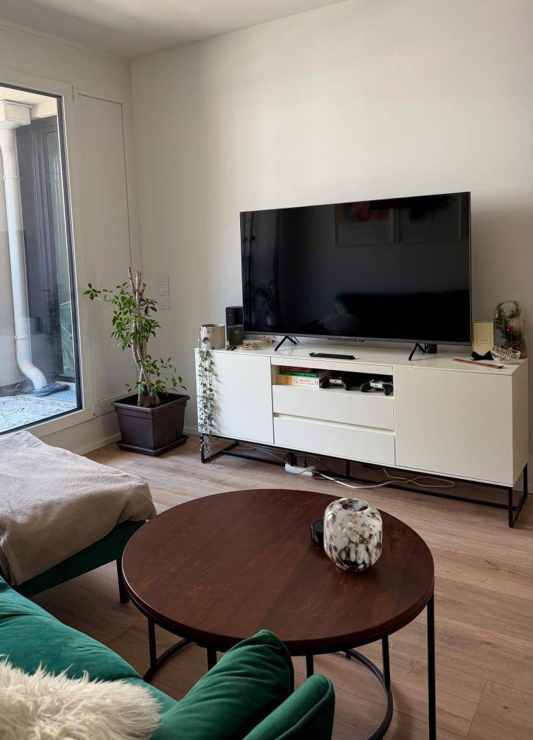 Wohnzimmer mit großem Fernseher, modernem Sideboard und Zugang zu einem Außenbereich.