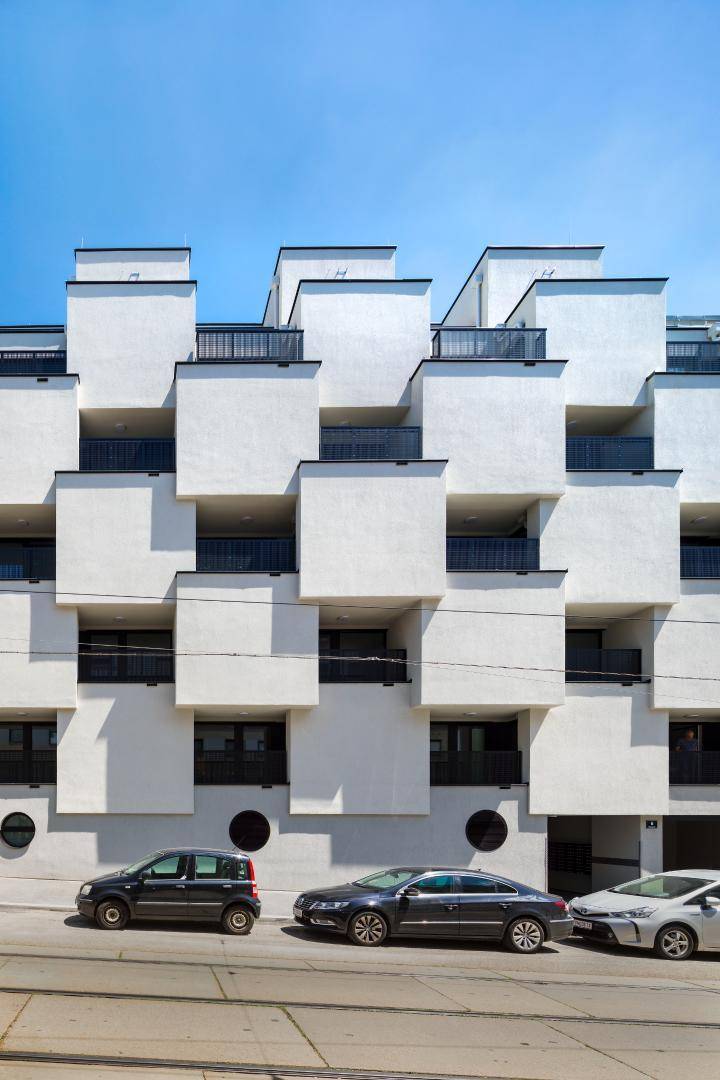 Moderne Wohnhausfassade mit gestaffelten Balkonen und klaren Linien.