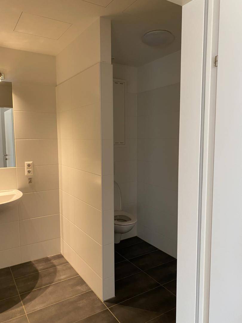 Helles Badezimmer mit Waschbecken und separatem WC-Bereich, modern gefliest und funktional.