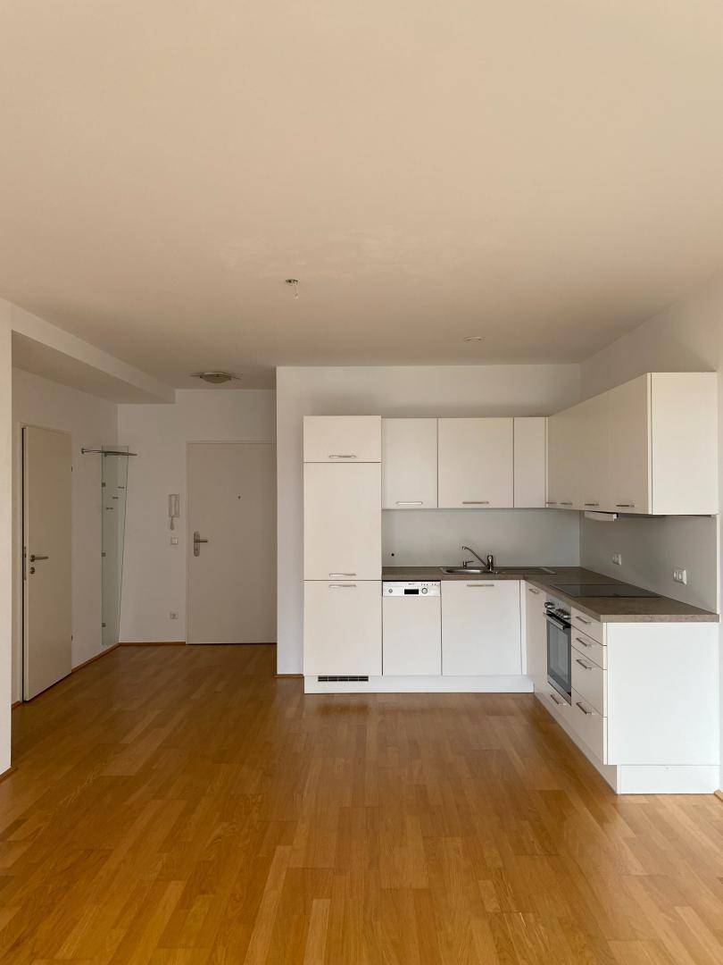 Moderne Einbauküche mit weißen Schränken und Holzparkett in offenem Wohnbereich integriert.
