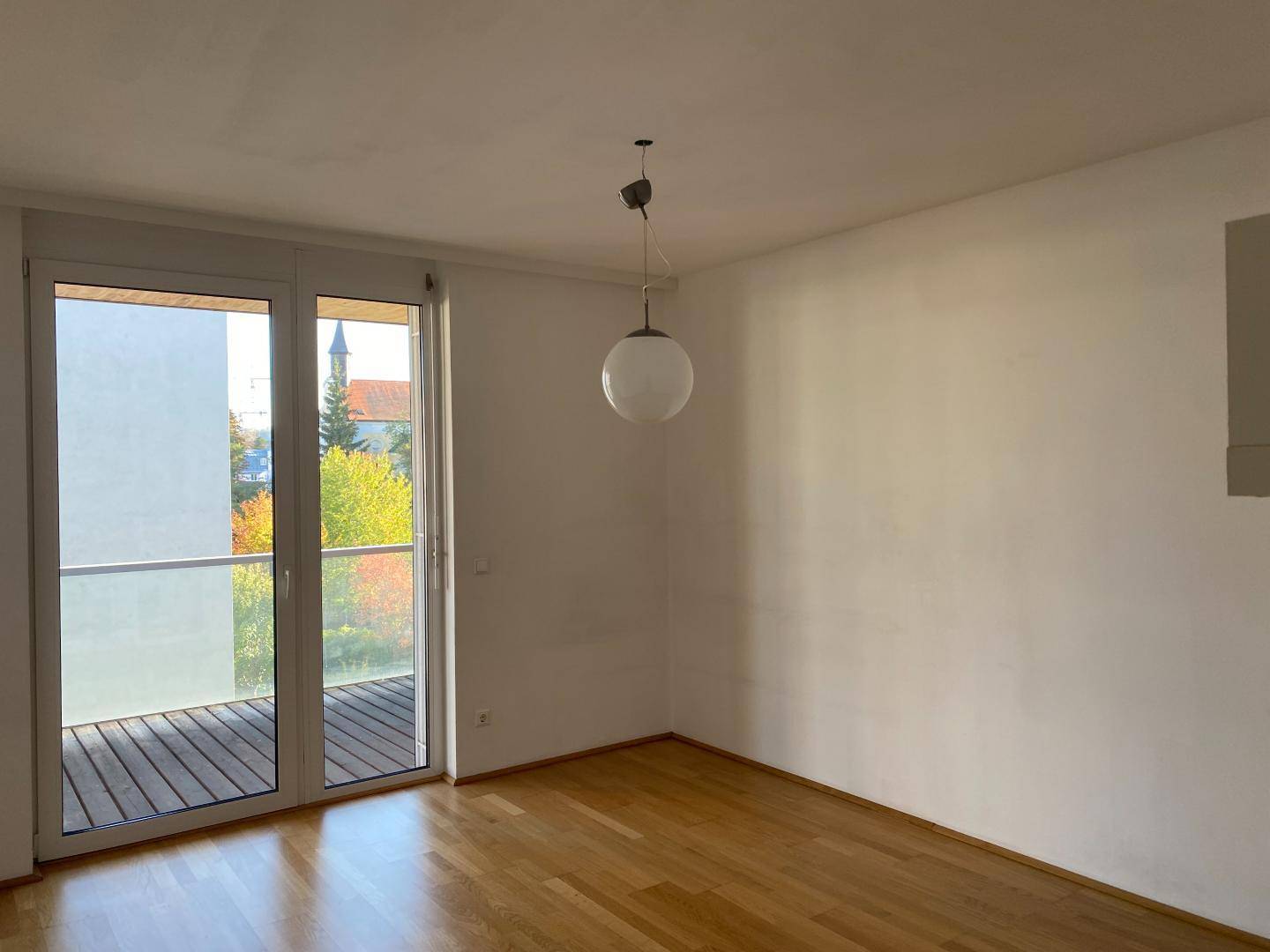 Geräumiges Schlafzimmer mit Holzboden und Balkonzugang, bietet einen Blick auf die Umgebung.