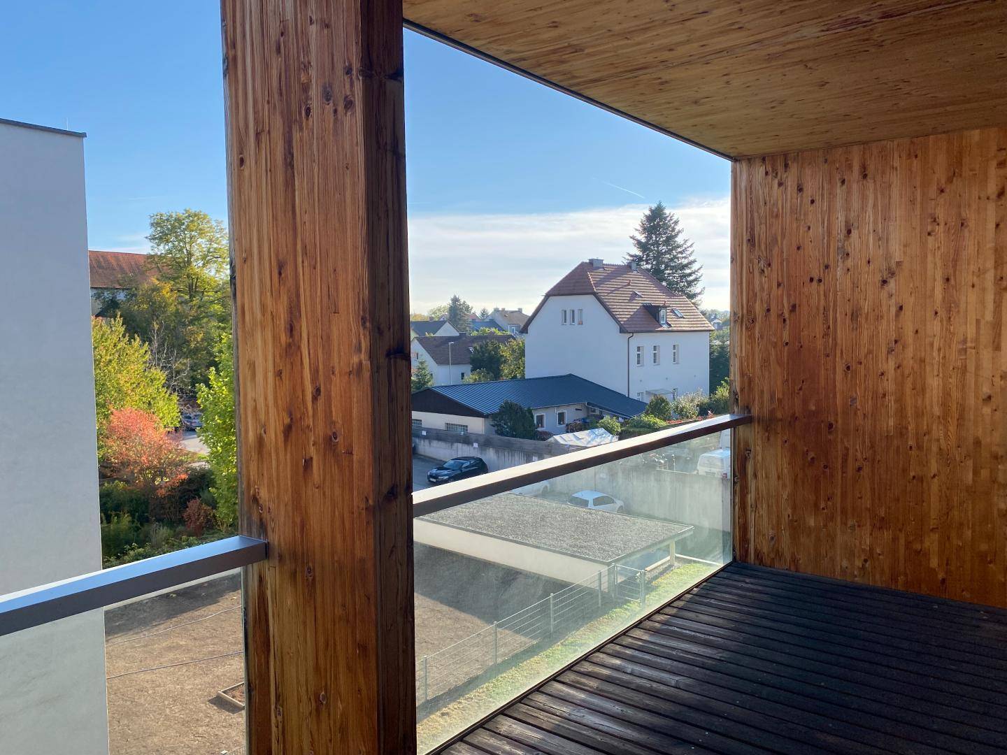 Heller Balkon mit Holzverkleidung und weitem Blick über die Wohngegend.