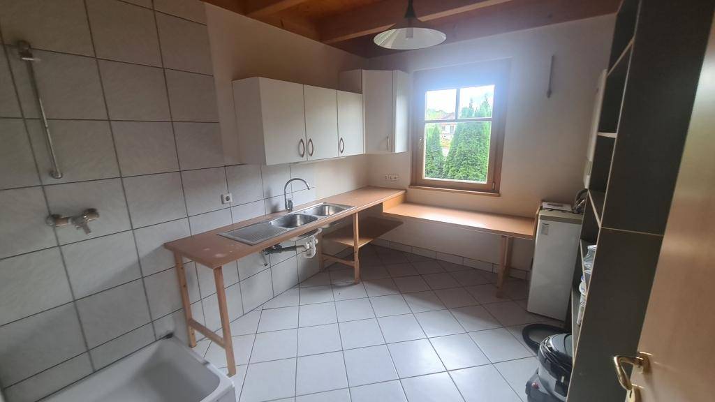 Praktischer Hauswirtschaftsraum mit Waschbecken, Arbeitsplatte und Fenster.