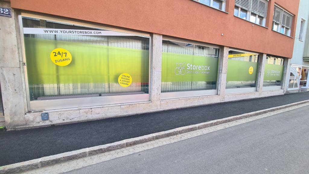 Nahaufnahme der Schaufensterfront eines Geschäfts mit grünen Werbefolien.