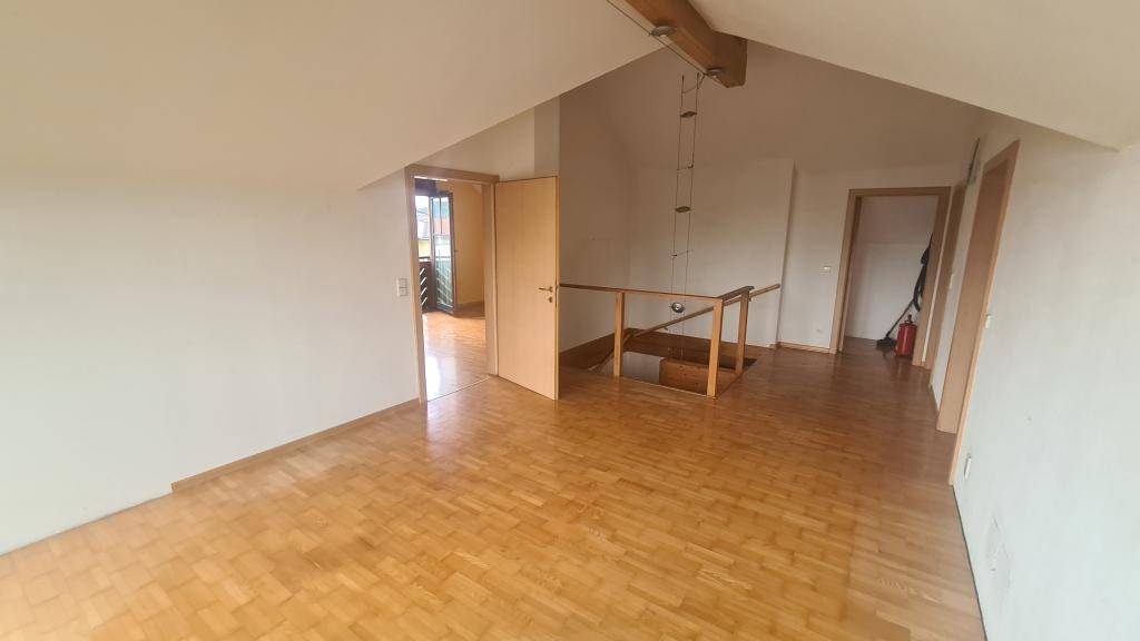 Geräumiger Obergeschossbereich mit Holzparkettboden und Zugang zu weiteren Räumen.